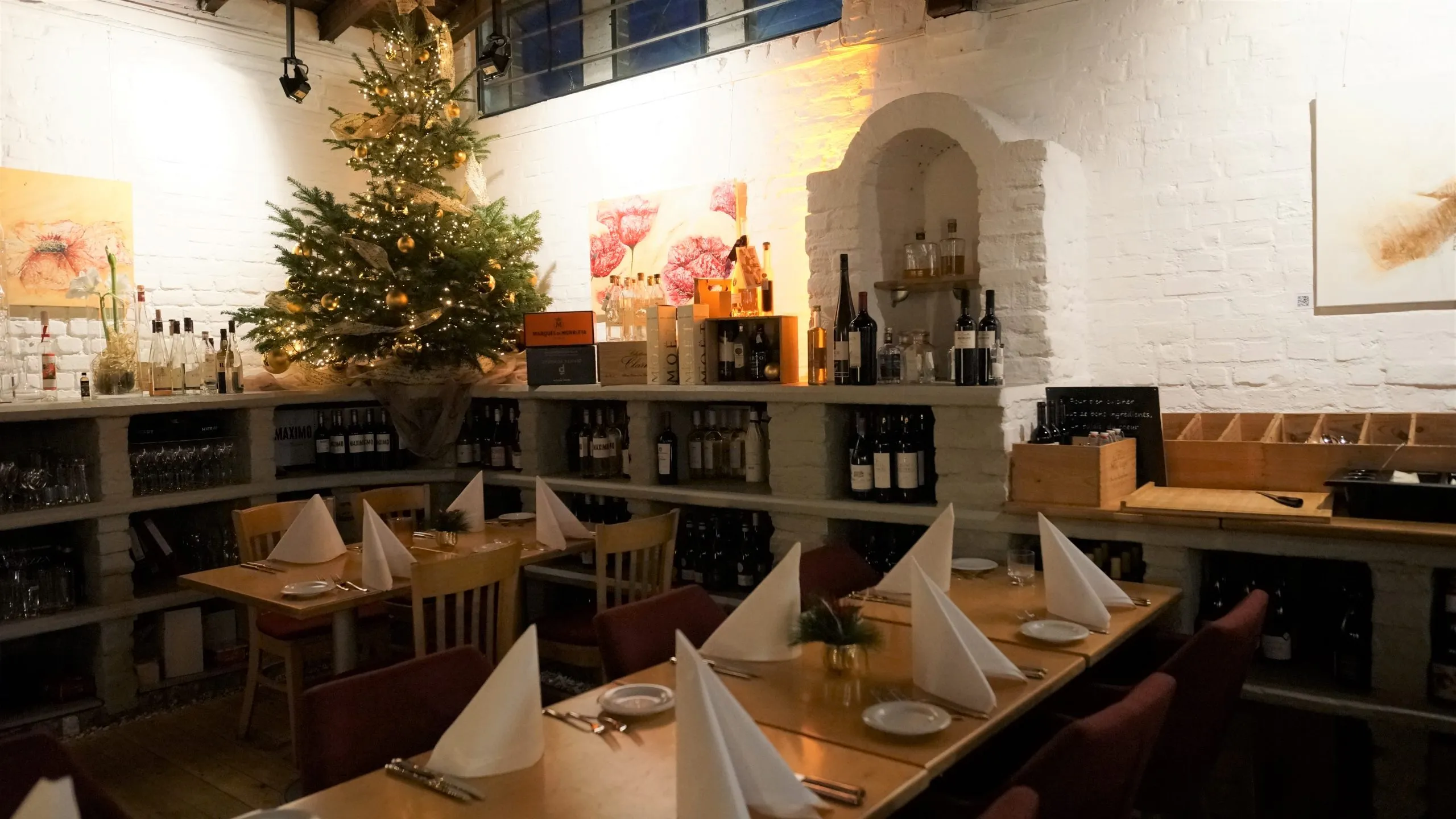Weihnachtlich geschmückter Gastraum der WeinGalerie mit beleuchtetem Tannenbaum und gedeckten Tischen